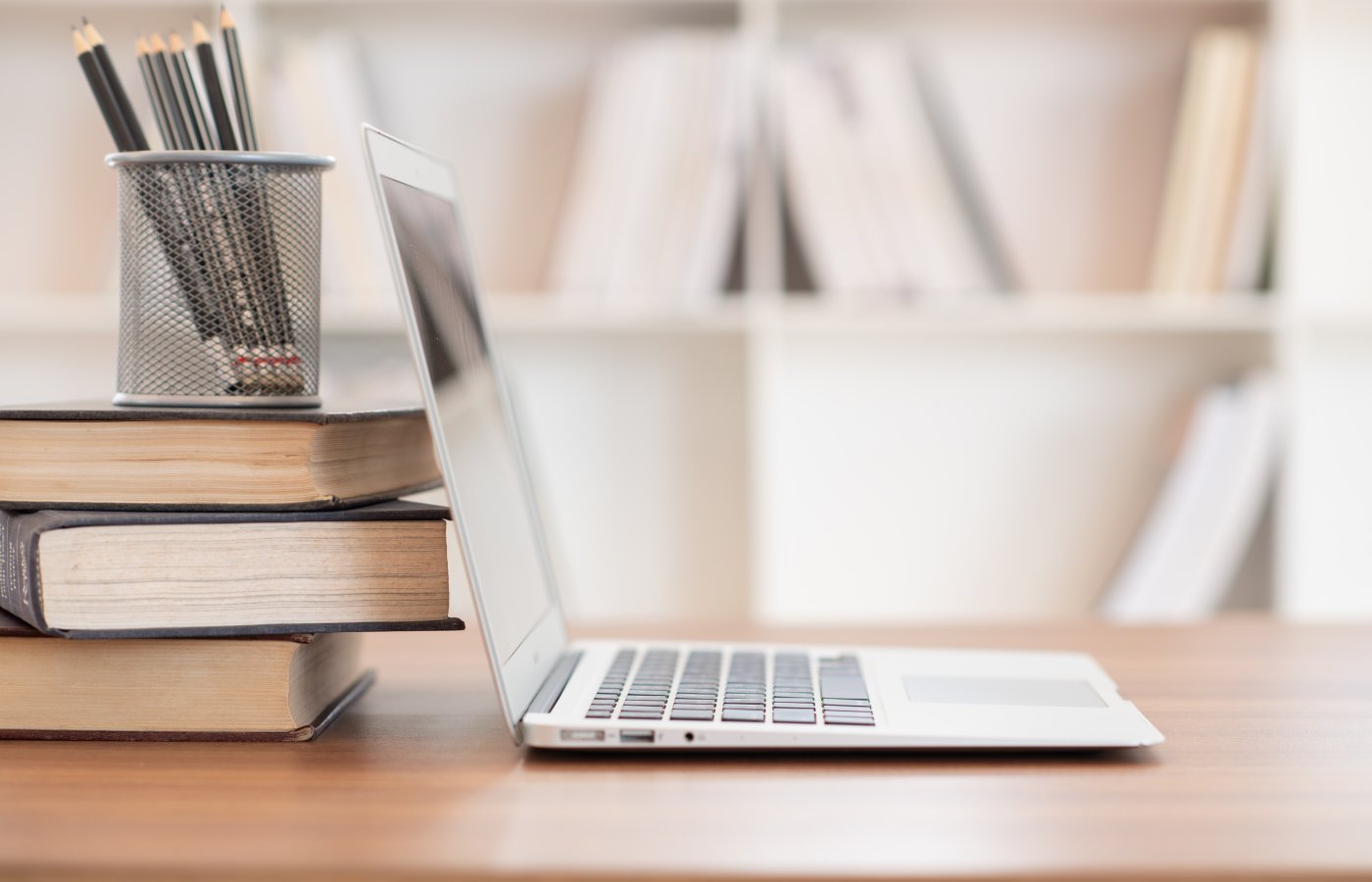 open laptop next to stack of books 