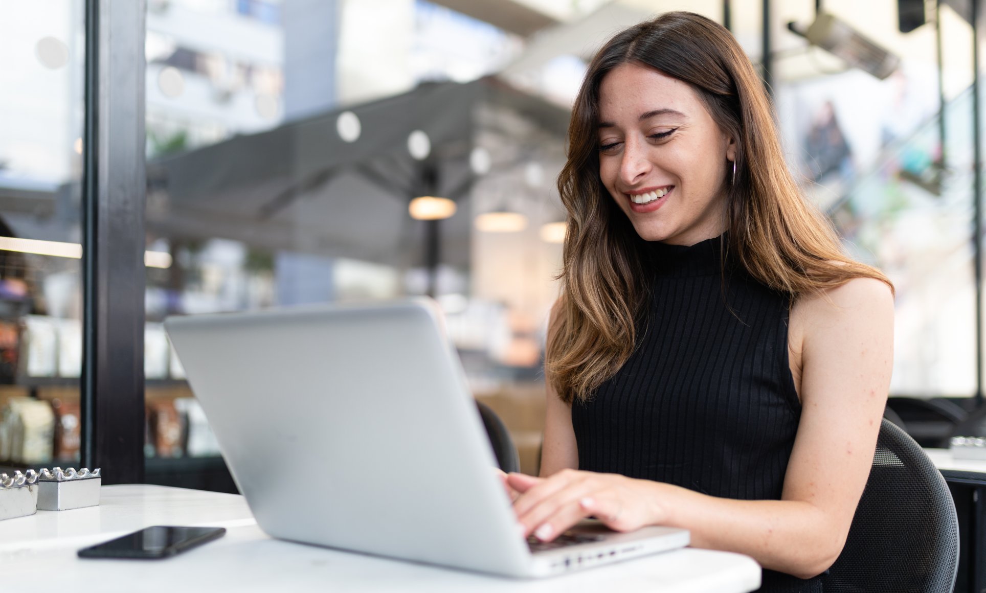 woman outside on laptop smiling