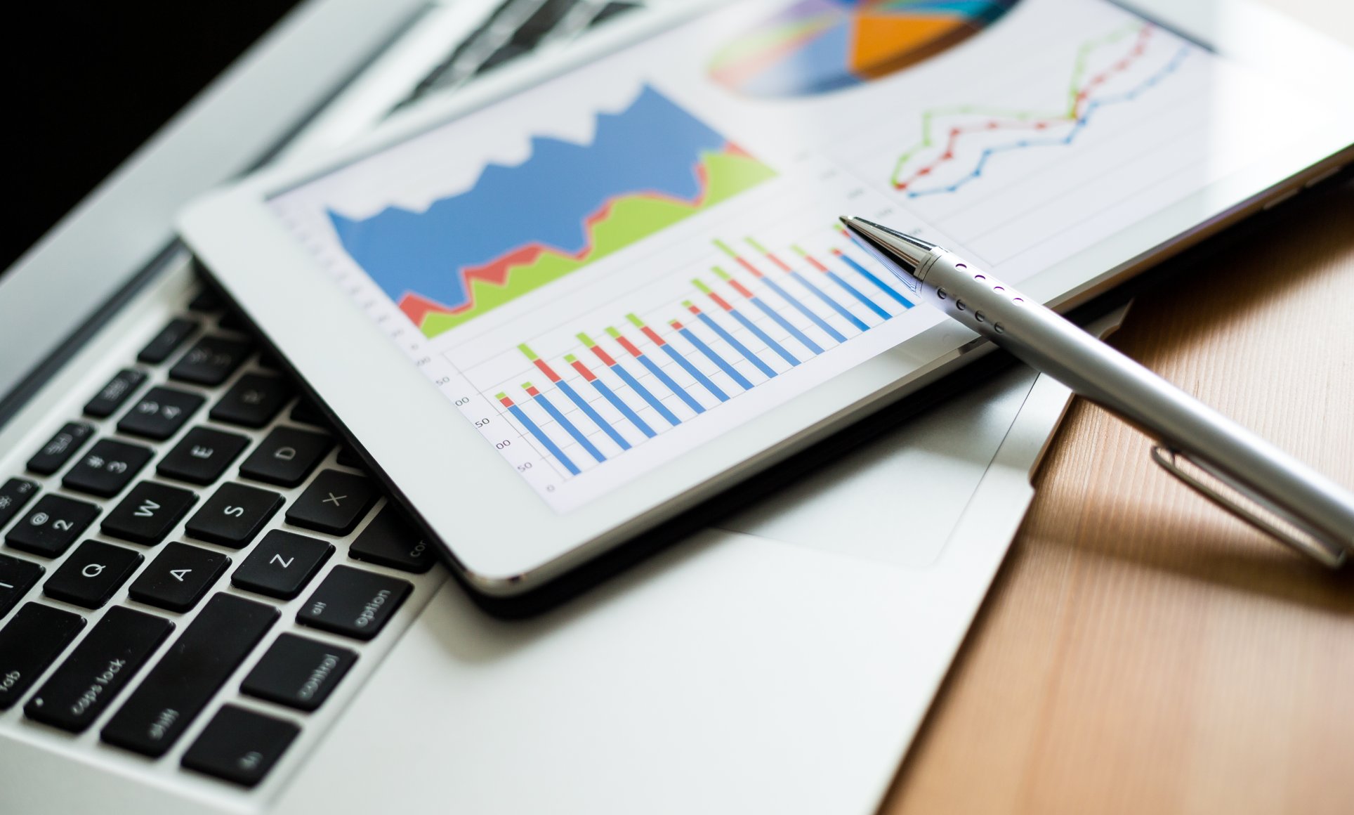 close up of computer and tablet with line and bar graphs