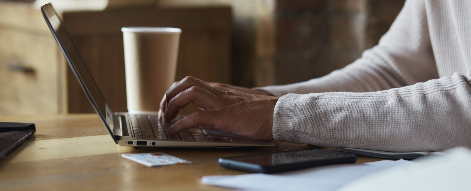 person typing on keyboard with coffee in background